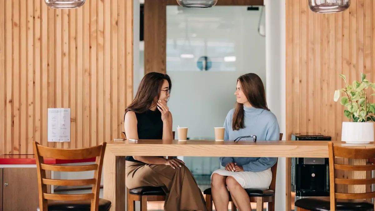 Dos amigas conversando en la mesa de una cafetería