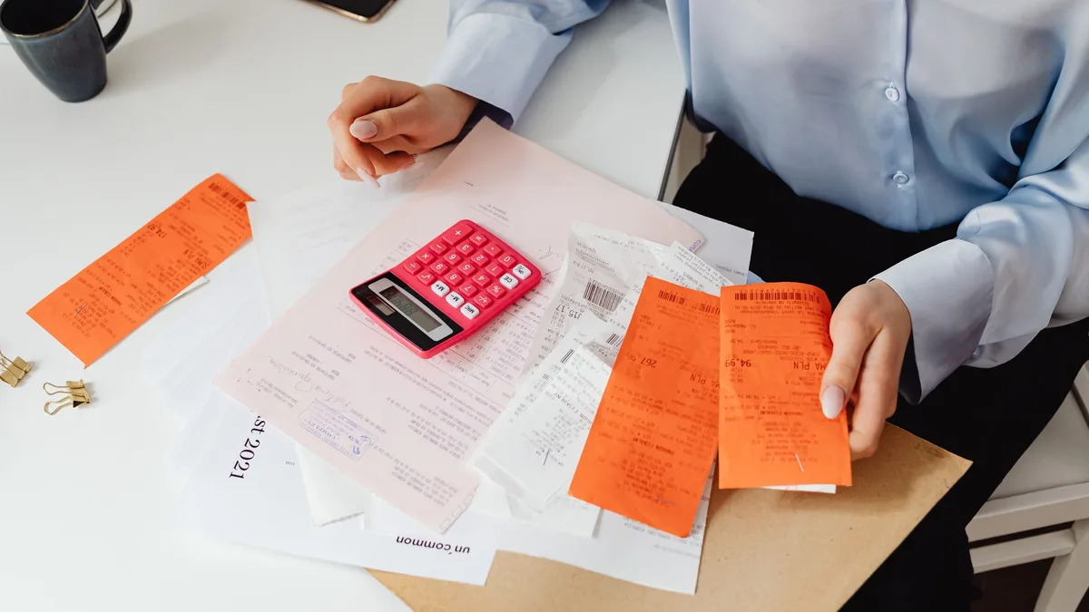 Persona revisando tickets y facturas con una calculadora sobre la mesa