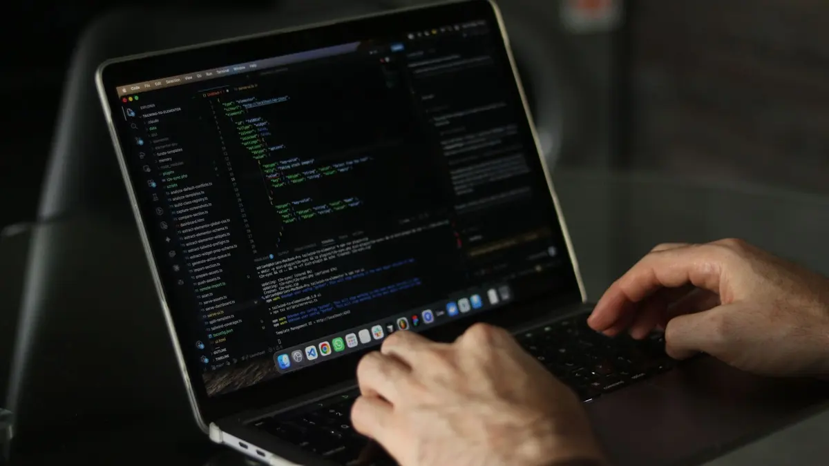 Manos de un desarrollador revisando y actualizando el código de una web en un portátil, parte de nuestro servicio de mantenimiento web